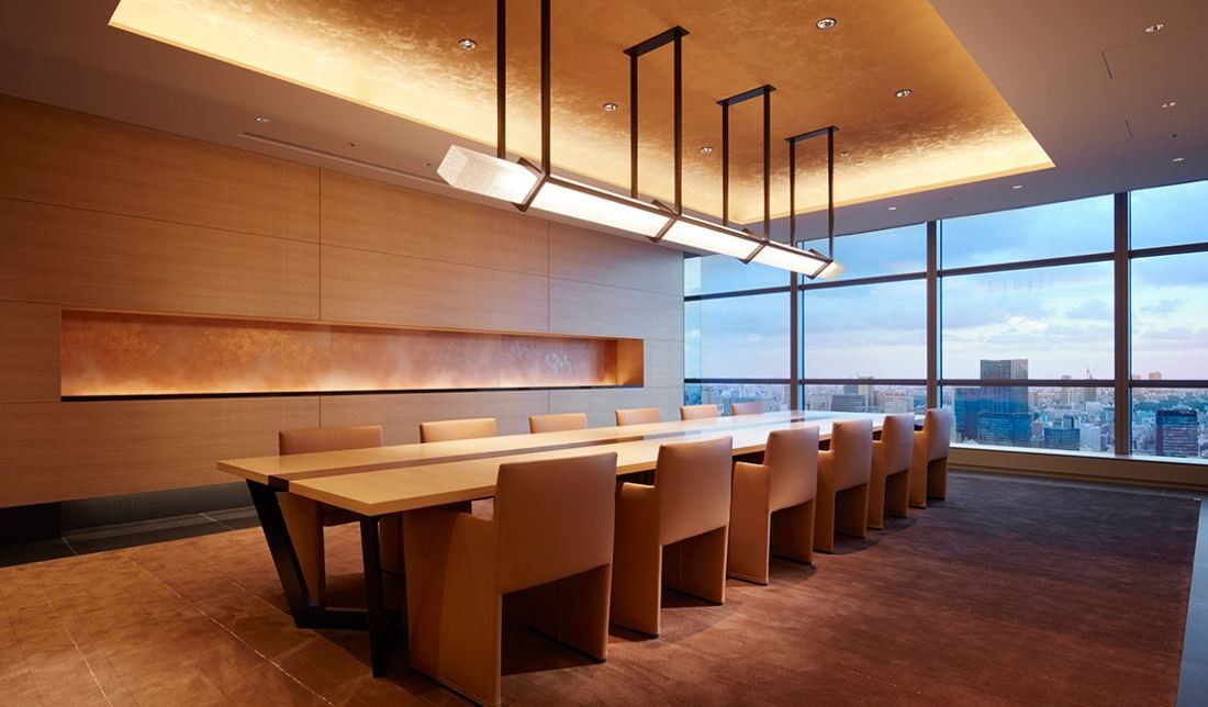 Sumitomo Corporation: Meeting room with a long wooden table, leather chairs and a city view at dusk