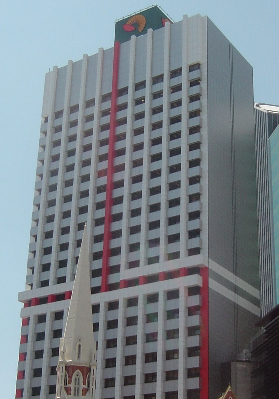 A tall white office tower with red vertical stripes and the Suncorp sun logo on top