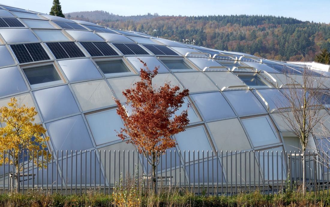 The Swatch Group: Curved façade of translucent, opaque and solar panels in a diamond grid, with autumn trees in front