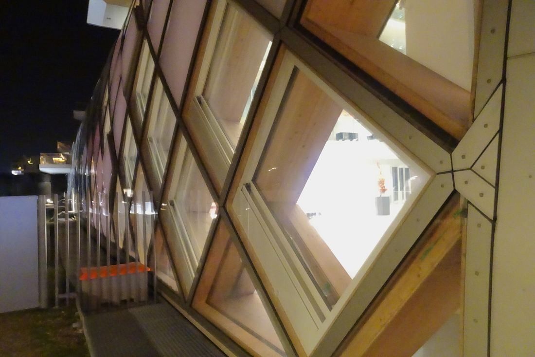 The Swatch Group: Diamond-shaped window openings set in wooden beams, seen at night