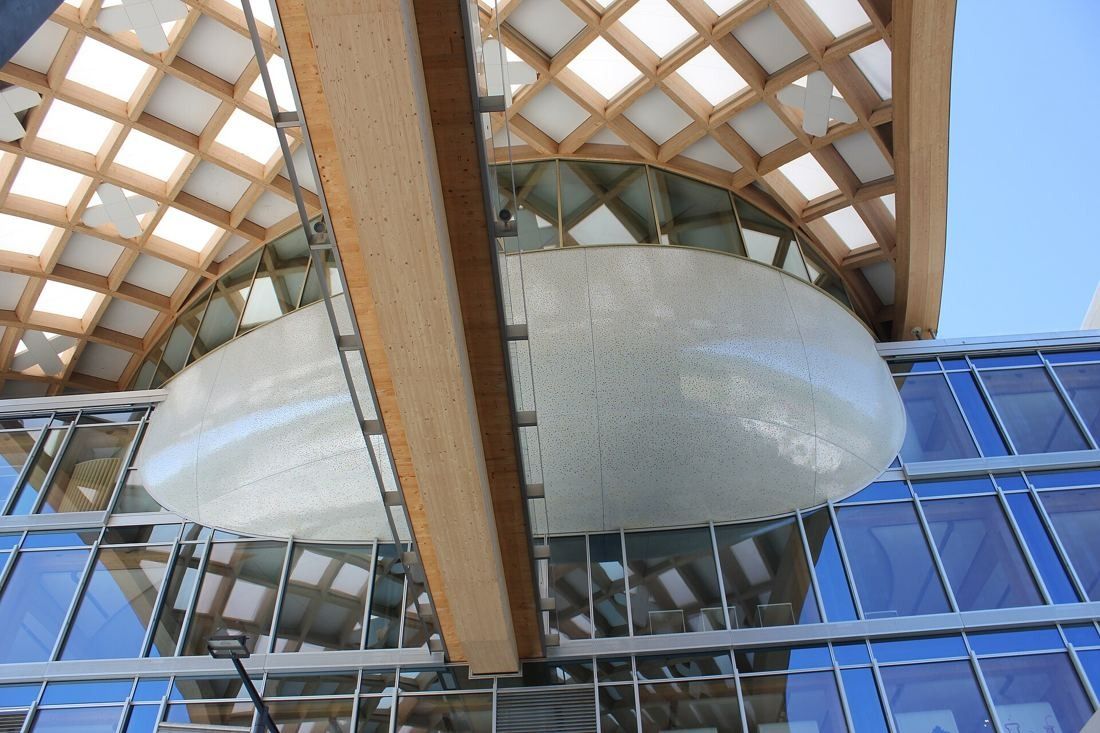 The Swatch Group: Looking up at the silver oval volume and a wooden beam under the timber lattice