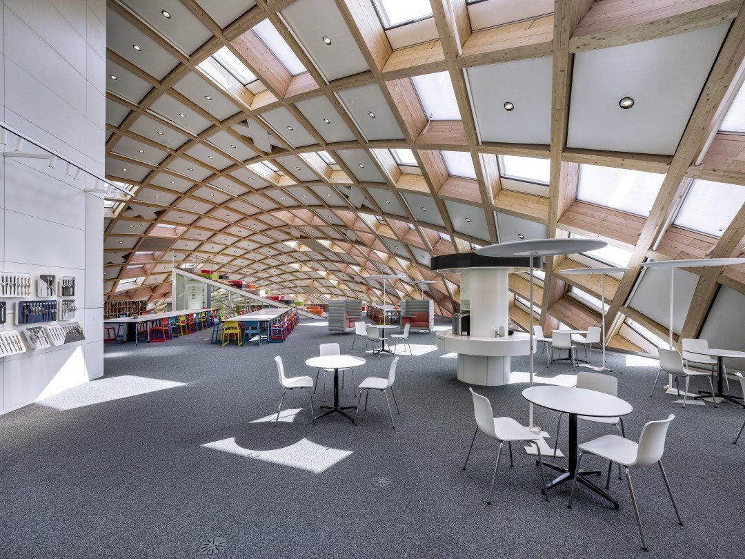 The Swatch Group: Open floor with round white tables and chairs under a curved timber lattice roof