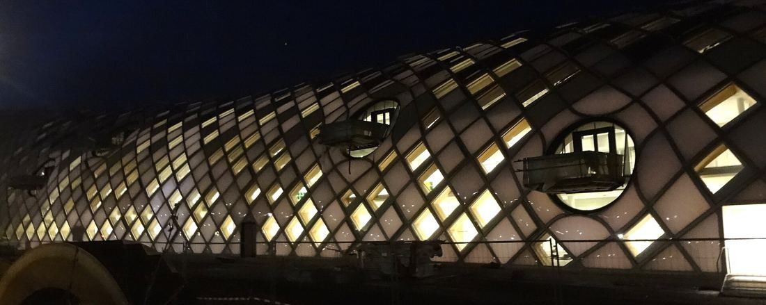 The Swatch Group: The diamond-patterned façade glowing from inside at night, with round balcony openings