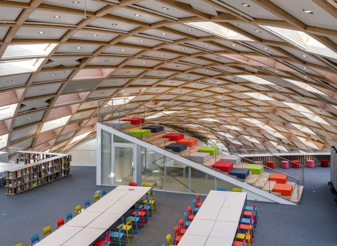 The Swatch Group: Timber lattice vault over an open floor with long tables, colourful chairs and a stepped seating staircase