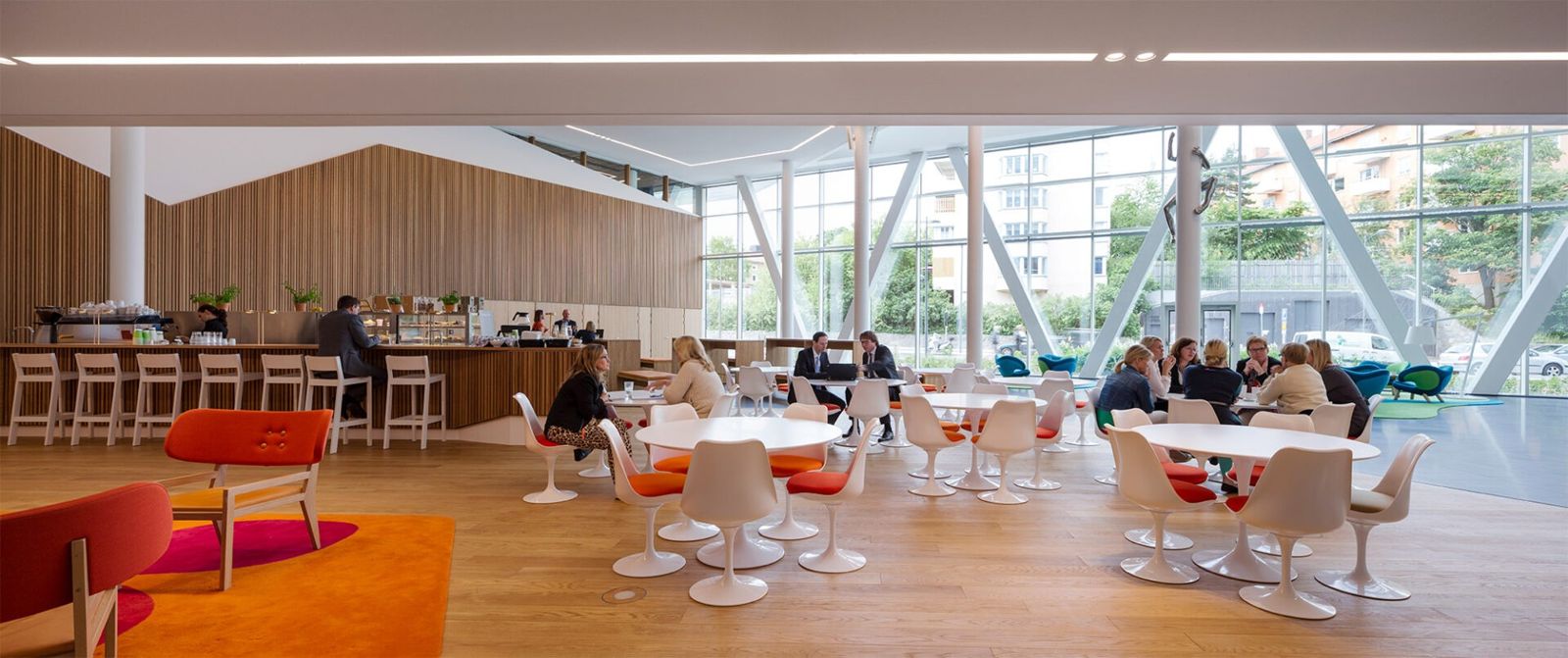 Swedbank: A restaurant with round tables and red chairs by tall windows