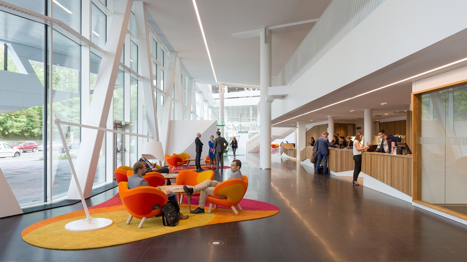 Swedbank: Orange chairs on a round rug in a long glass hall