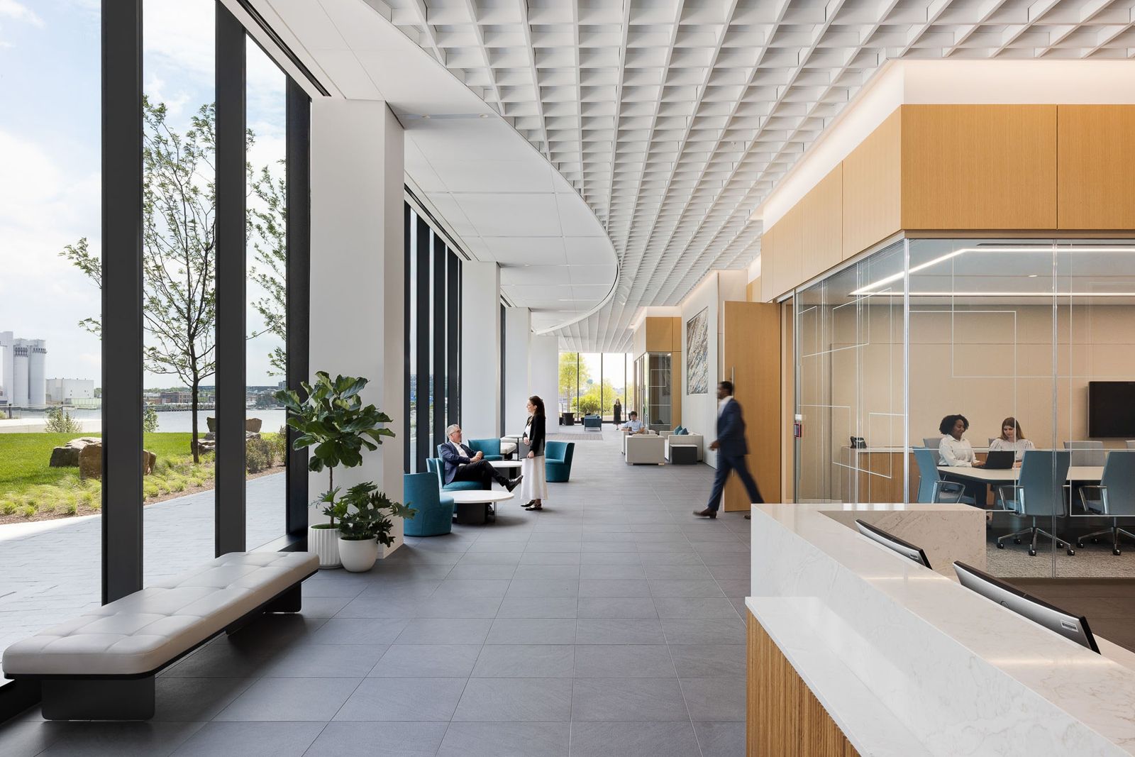 T. Rowe Price: A long bright corridor with a reception counter and glass meeting rooms