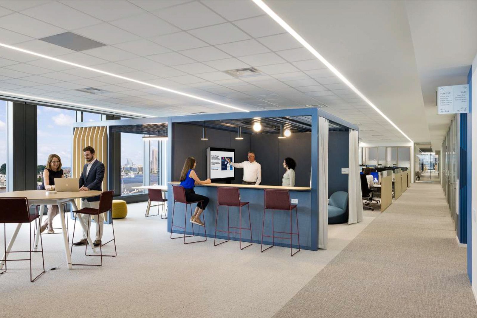 T. Rowe Price: An open team room with high stools and a screen