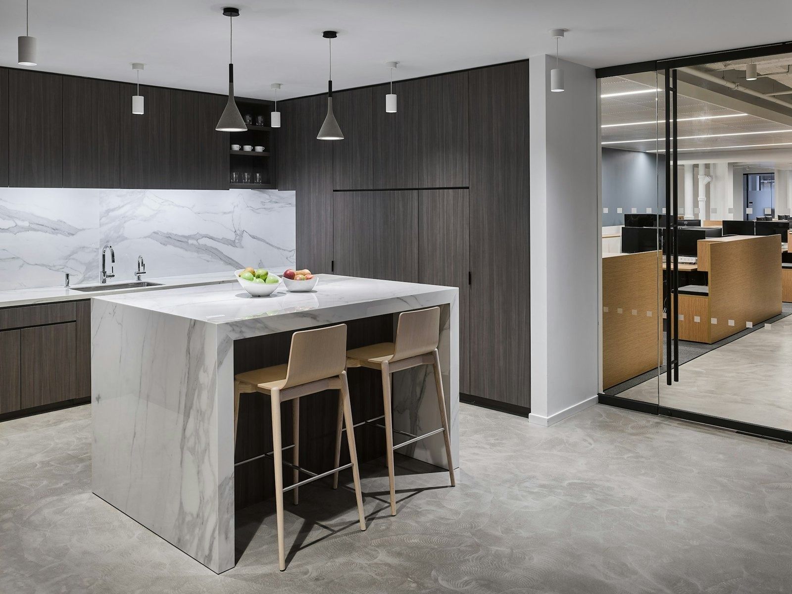 Take-Two Interactive: Kitchen island in white marble with two stools and dark cabinets