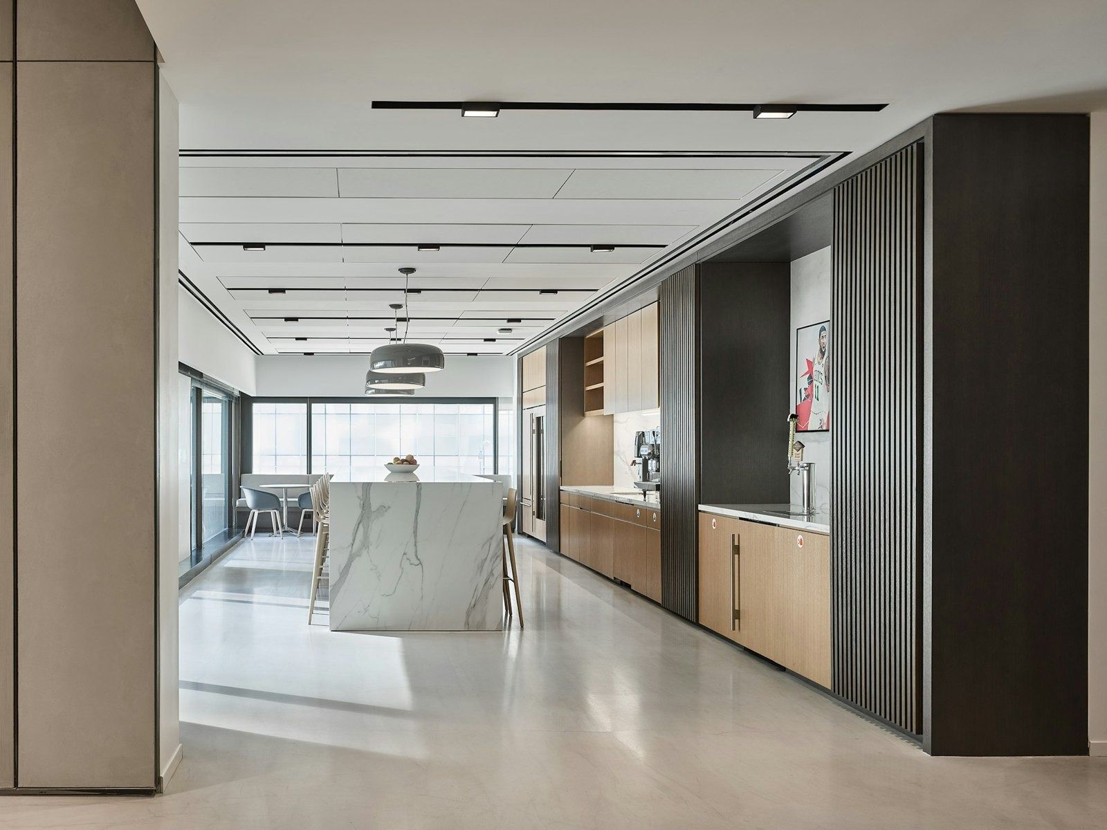 Take-Two Interactive: Long pantry with a marble island, wood cabinets and windows at the end