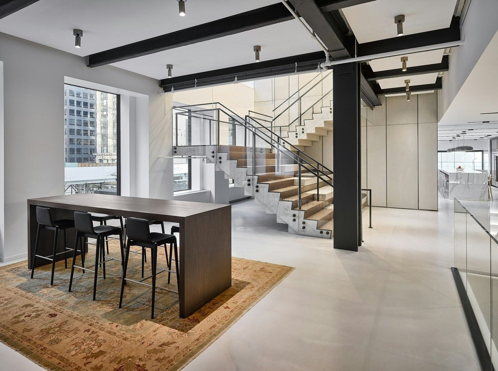Take-Two Interactive: Open floor with a high table and stools beside a light wooden staircase and steel beams