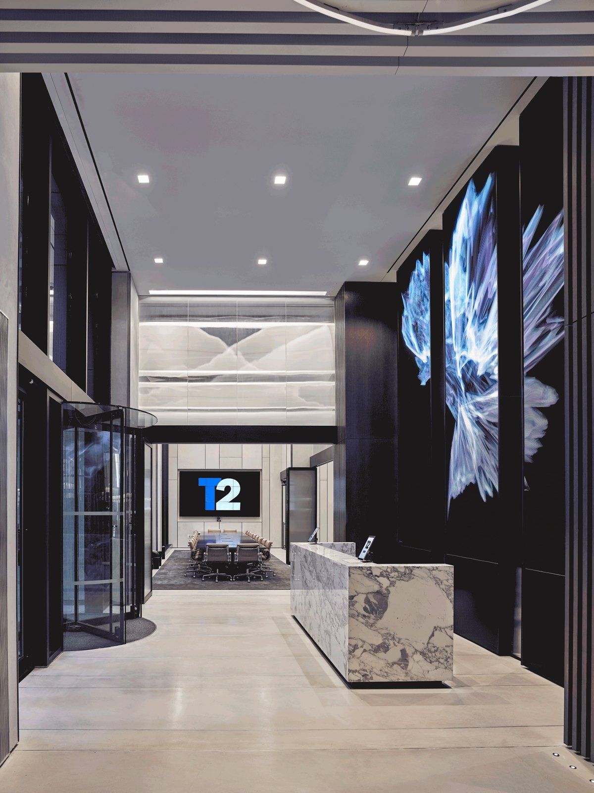 Take-Two Interactive: Reception desk in a tall lobby with large illuminated artwork panels and revolving doors
