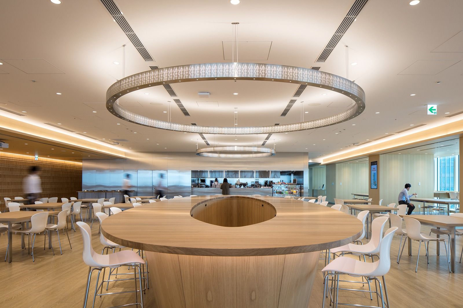 Takeda: Bright cafeteria with a round timber table and a ring-shaped light