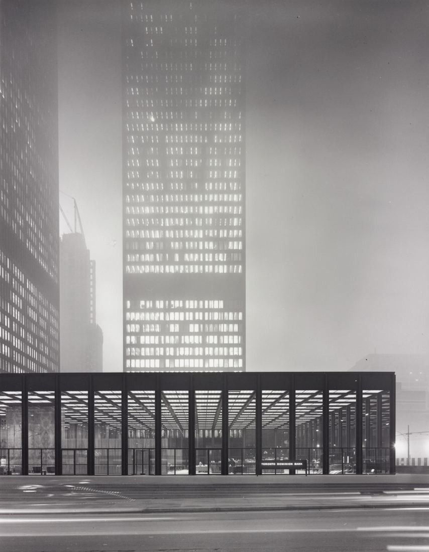 Black-and-white photo of a tall dark tower and a low pavilion in fog