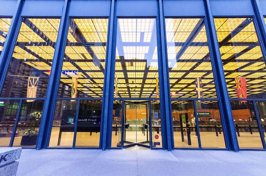 TD Bank Group (The Toronto-Dominion Bank): Glass entrance wall with blue-painted steel mullions and a lit grid ceiling inside
