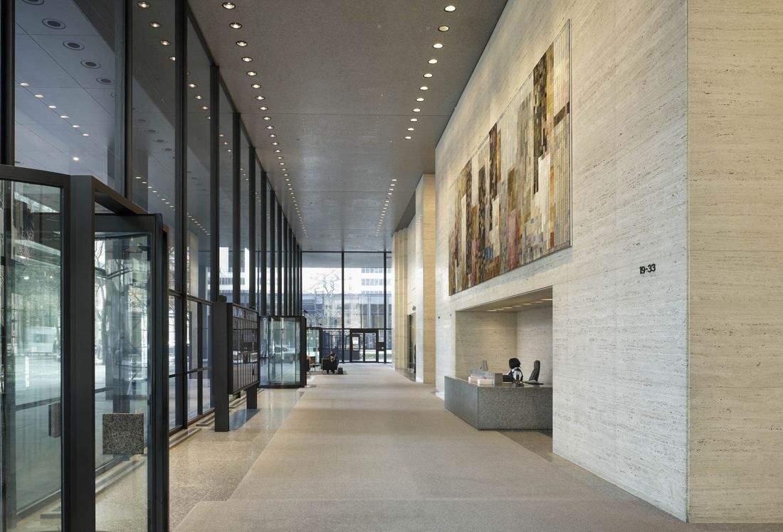 TD Bank Group (The Toronto-Dominion Bank): Long lobby with glass wall on one side, travertine wall with a large tapestry and a reception desk