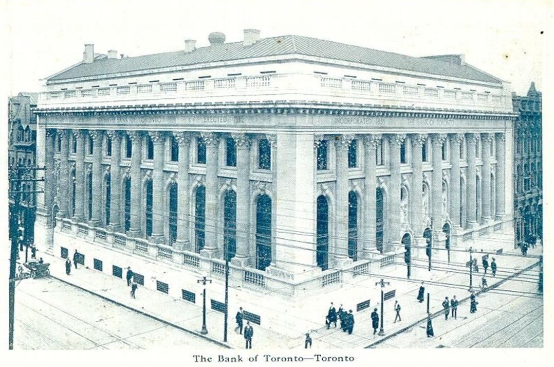 Postcard of a large neoclassical bank building with a row of columns on a street corner