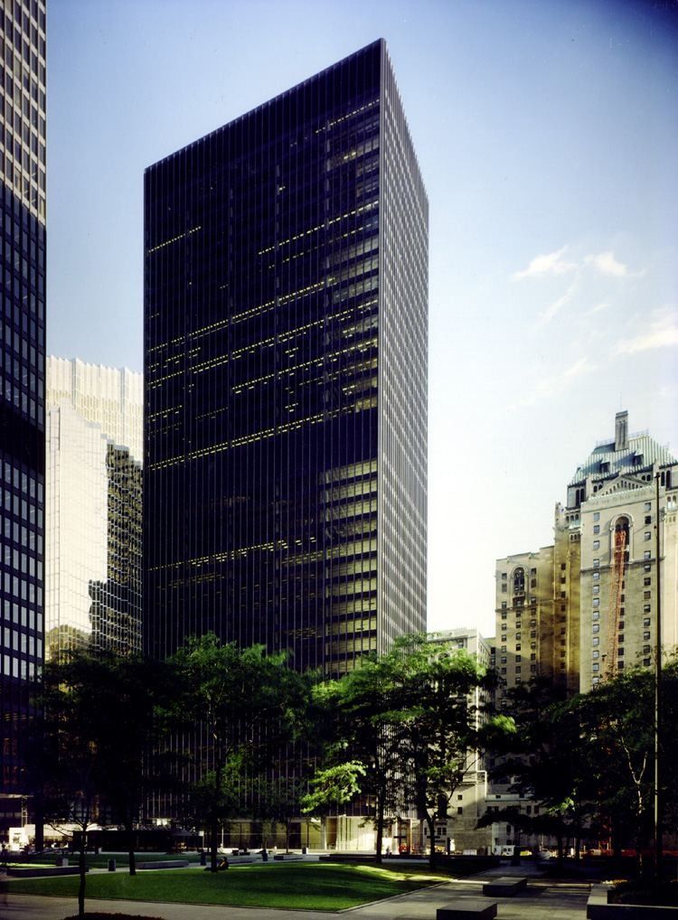TD Bank Group (The Toronto-Dominion Bank): Tall black tower rising behind trees on a plaza