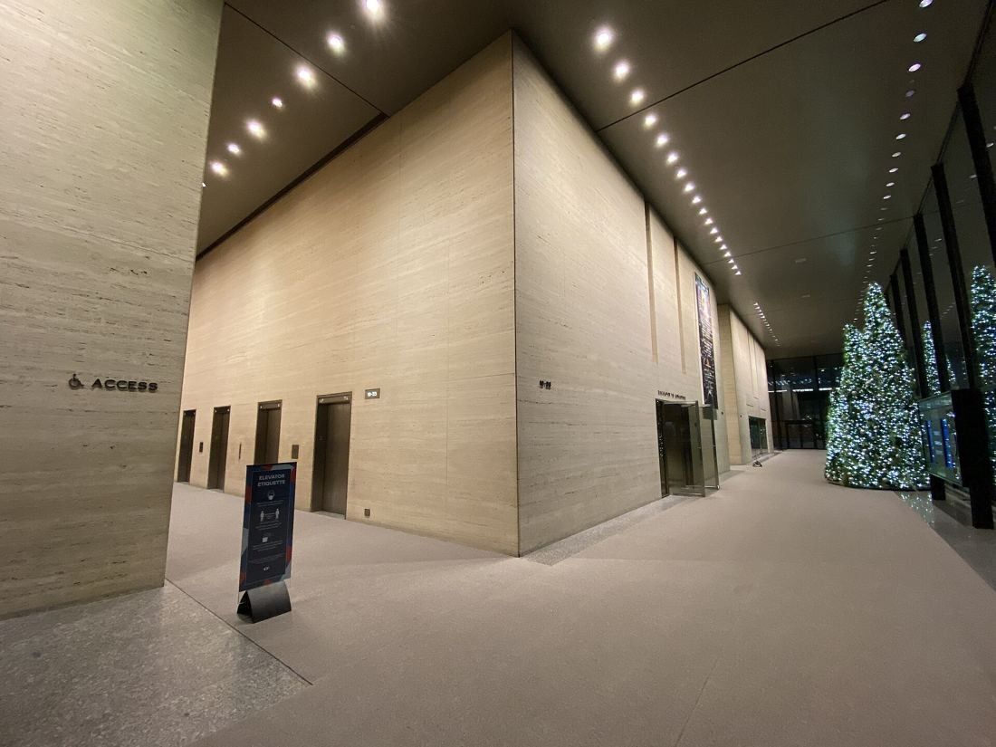 TD Bank Group (The Toronto-Dominion Bank): Tall lobby with travertine walls, elevator doors and a Christmas tree by the glass