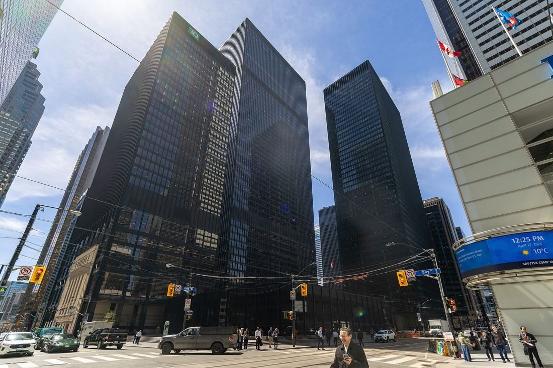 Two black steel-and-glass towers and a low glass pavilion seen from a street corner