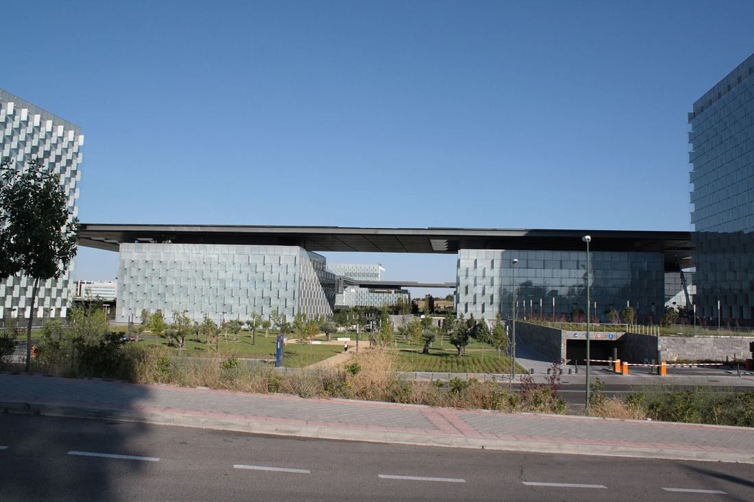 Telefónica: Campus behind a garden and a road, with a long flat canopy between two glass towers