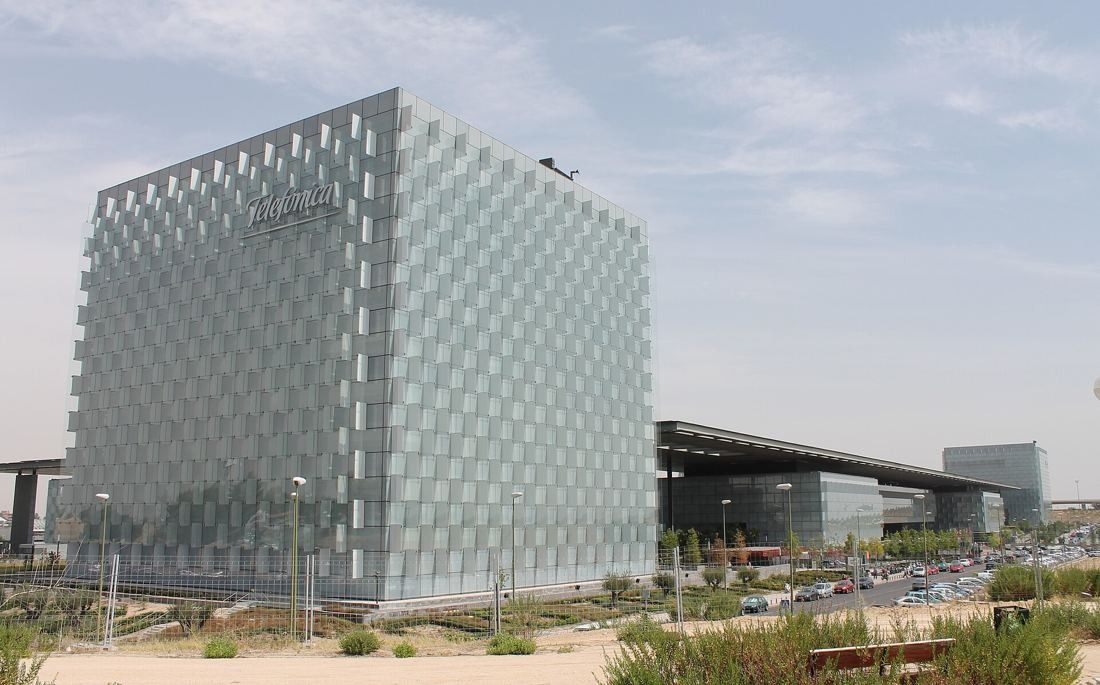 Telefónica: Glass tower seen across a planted verge, a canopy behind it