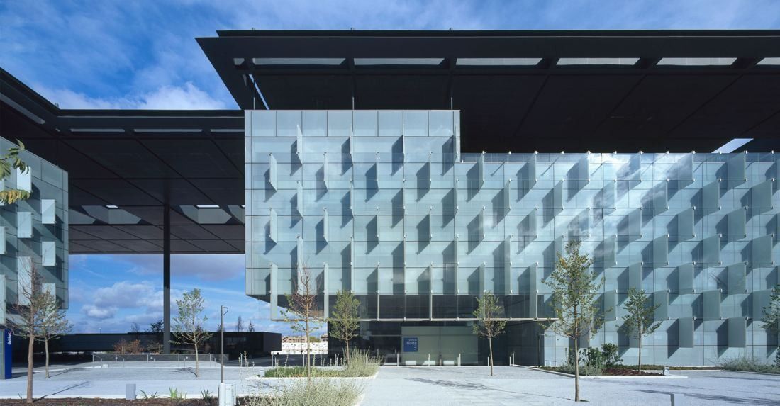 Telefónica: Glass tower with a pleated facade beside a long dark canopy over a paved square