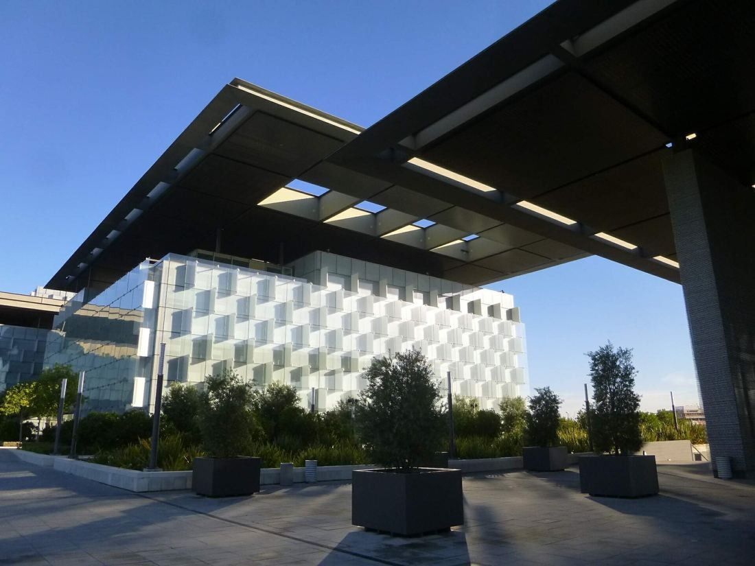 Telefónica: Overhanging canopy with skylight openings above planters and a glass building