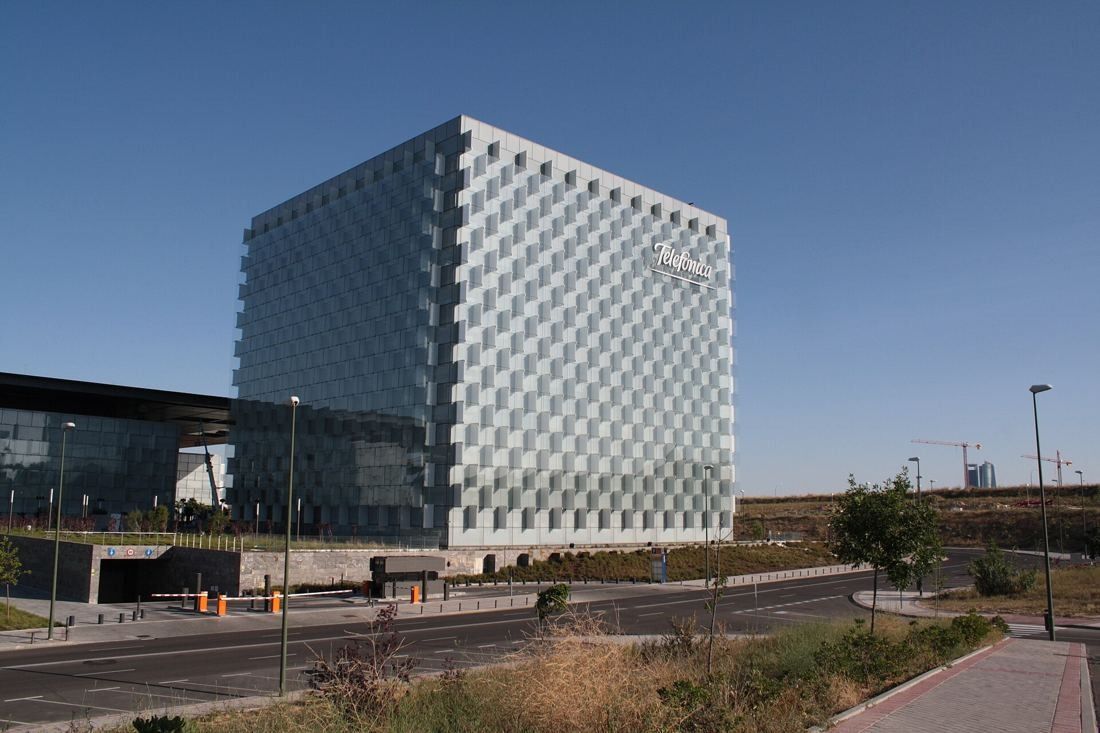 Telefónica: Square glass tower beside a road and low campus buildings