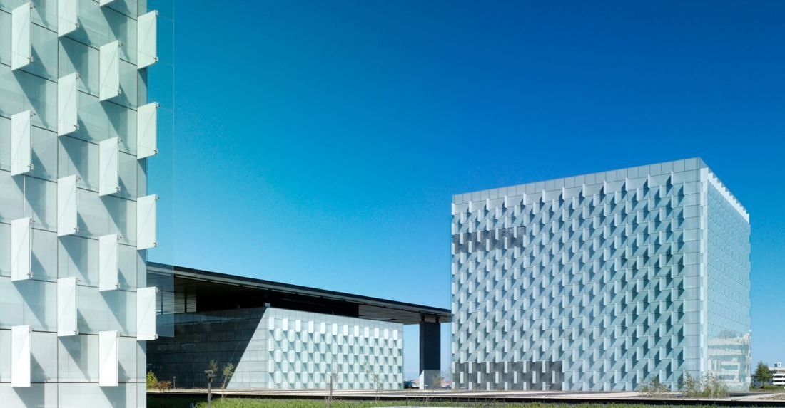 Telefónica: Two glass towers with pleated facades against a deep blue sky