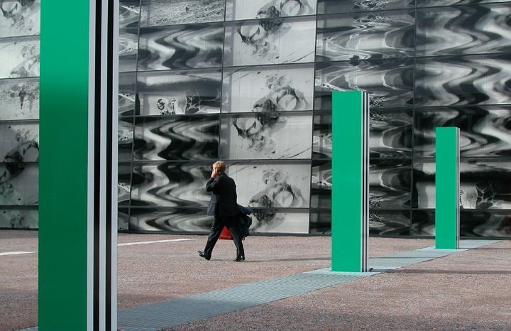 Telenor: Glass wall printed with large artwork and green columns, with a person walking past