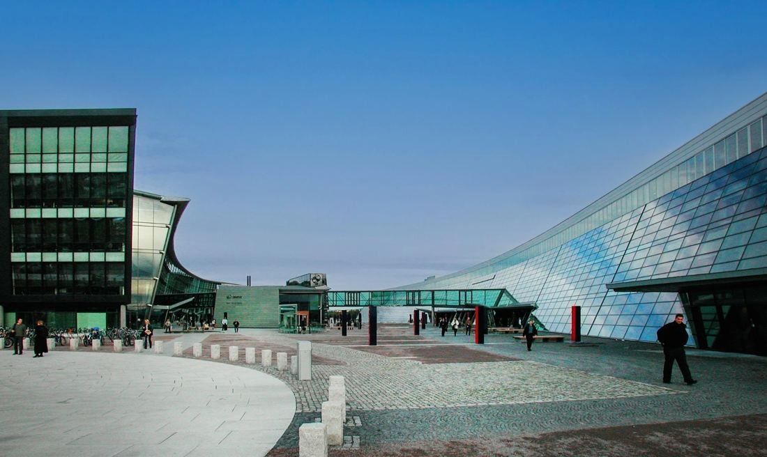 Telenor: Large open paved plaza between a dark office wing and a sweeping glass building