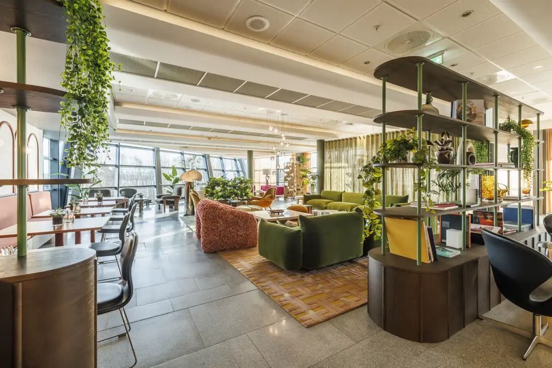 Telenor: Lounge with sofas, armchairs, plants and a shelving divider by large windows