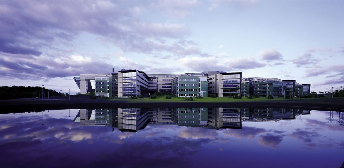 Telenor: Low office buildings reflected in still water under a purple sky