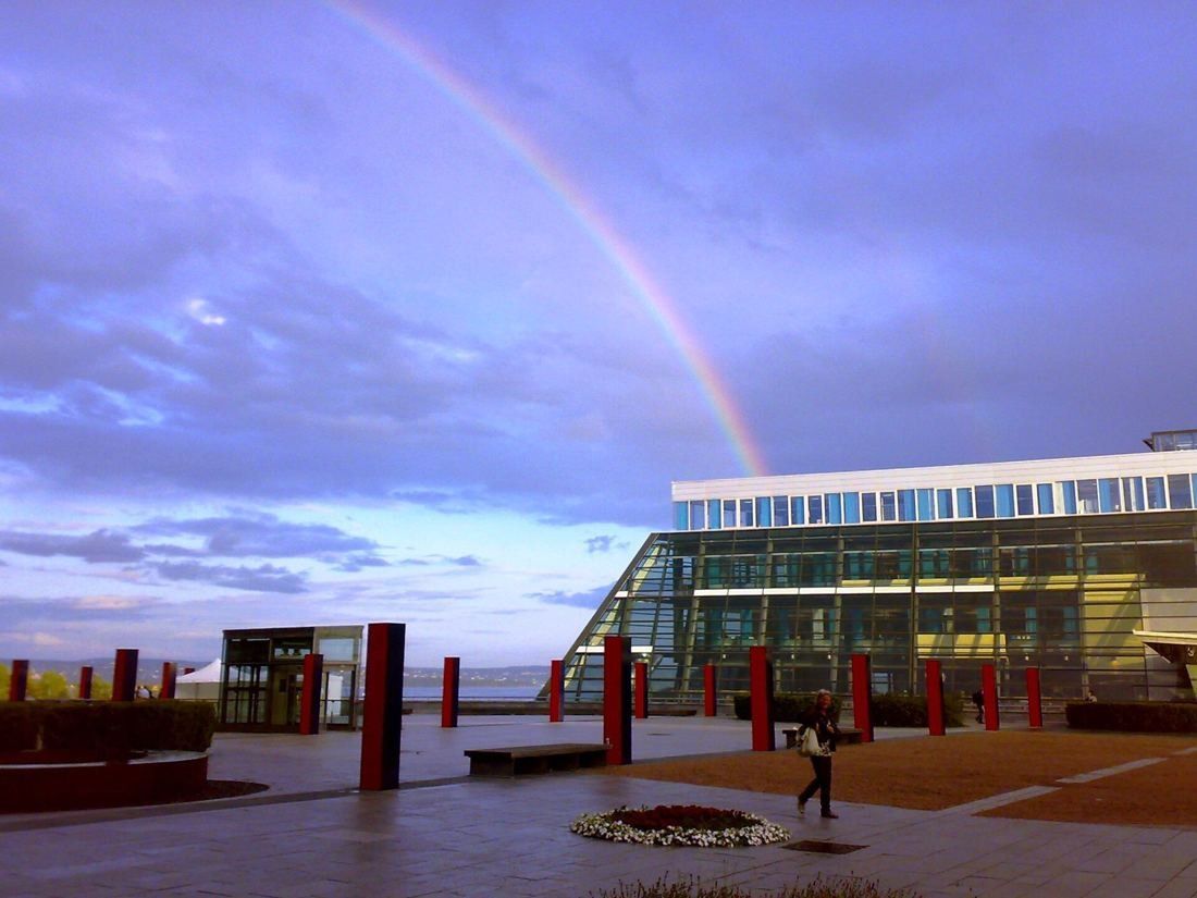 Telenor: Plaza with red columns and a glass building under a rainbow