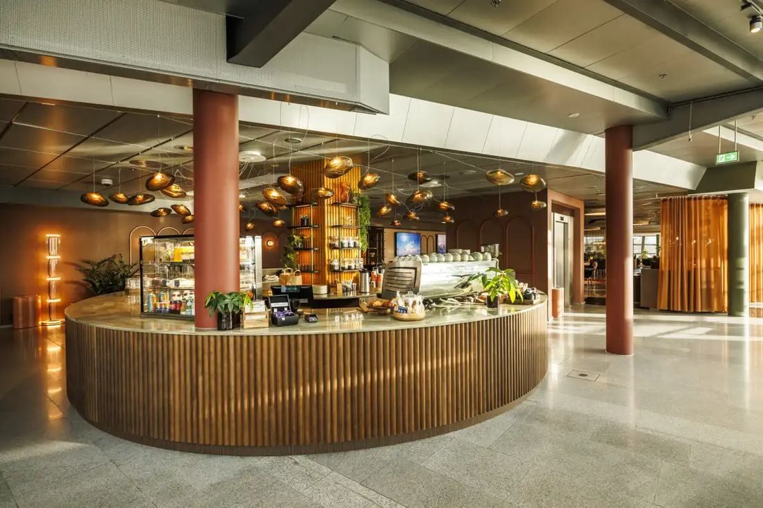 Telenor: Round wooden café counter with hanging lamps and shelves of plants in a spacious hall