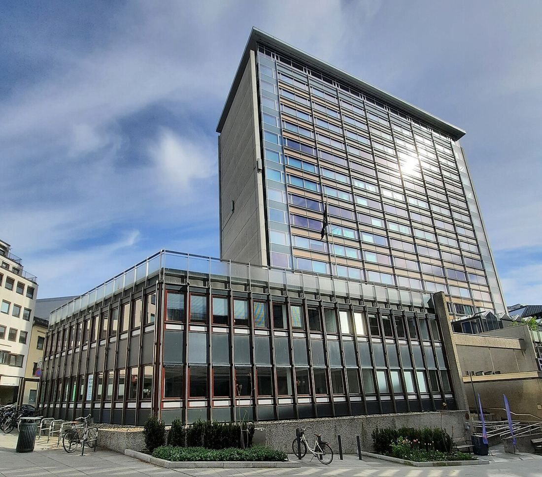 Tall glass office slab above a low glazed podium on an Oslo street corner