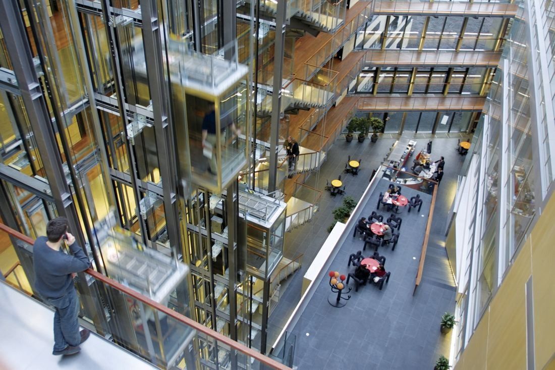 Telenor: View down into a tall atrium with glass lifts, wooden balconies and café tables on the ground floor