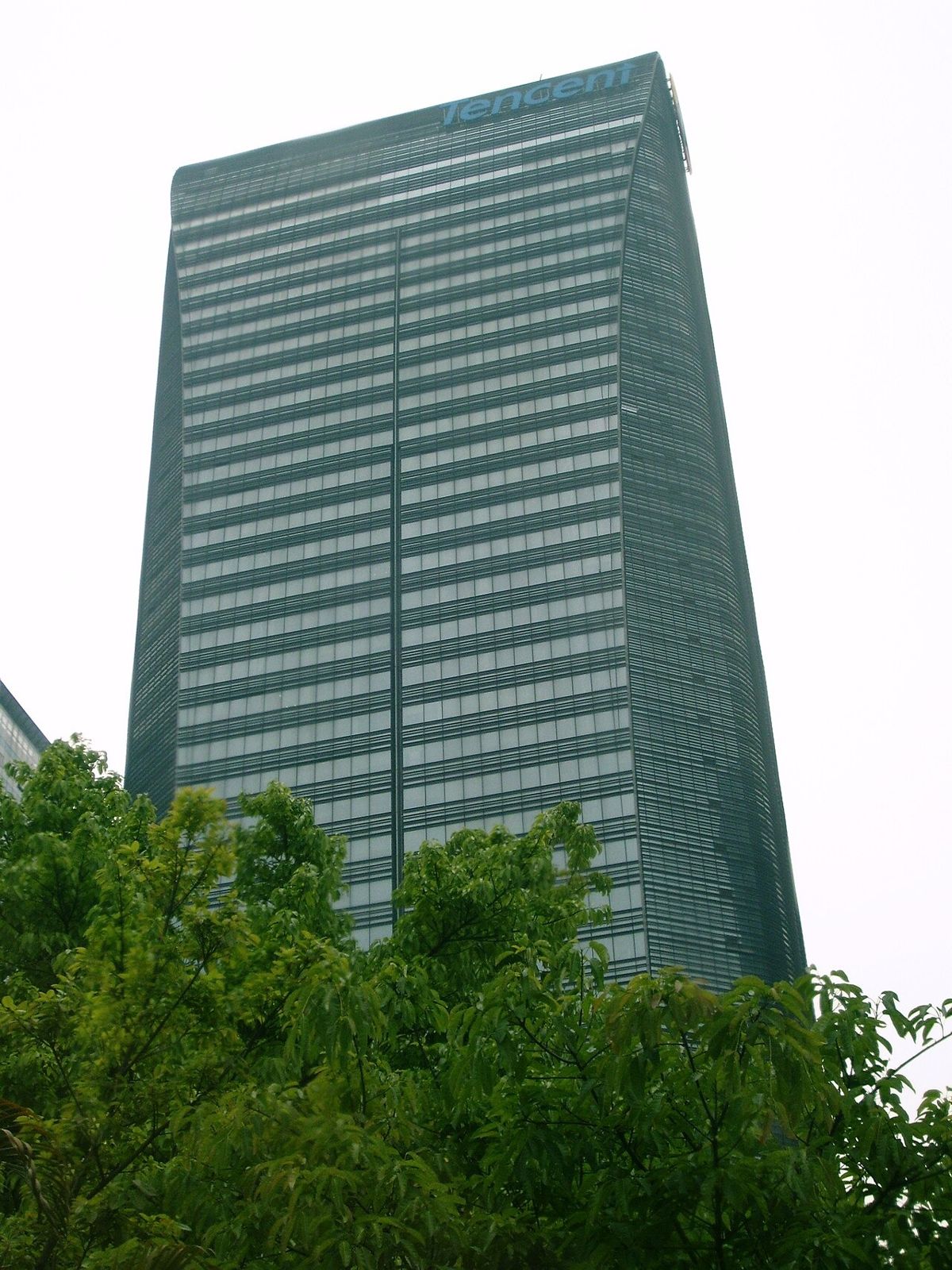 Tall glass office tower behind trees