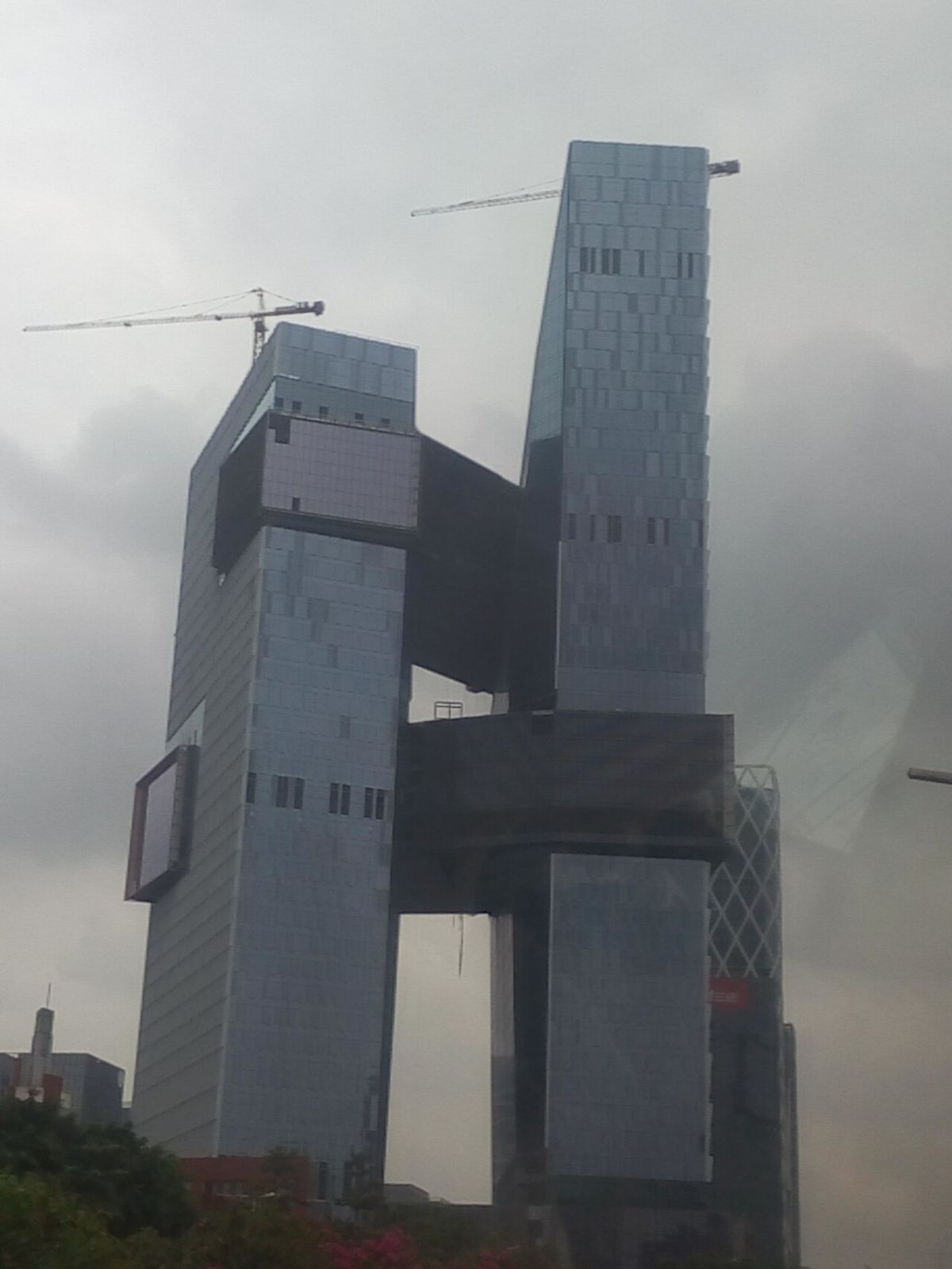 Two towers with protruding bridge blocks under construction, with a crane