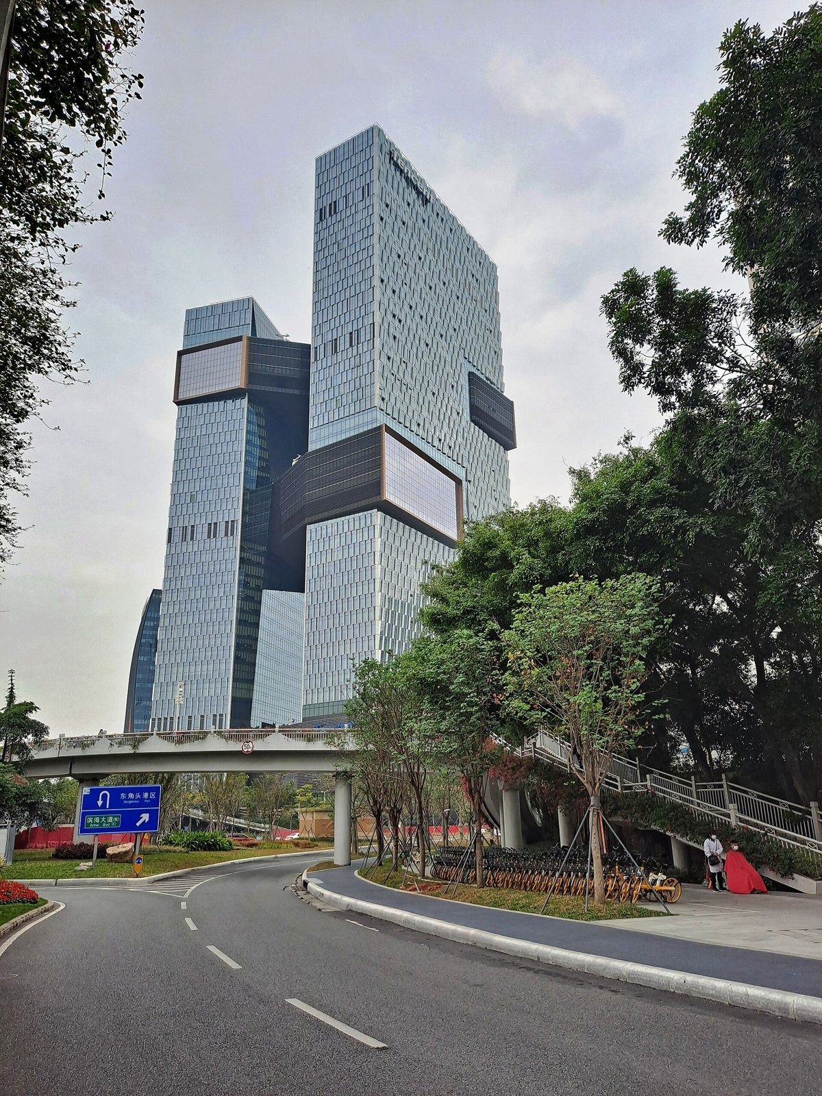 Tencent: Two towers rising beyond a curved road and trees