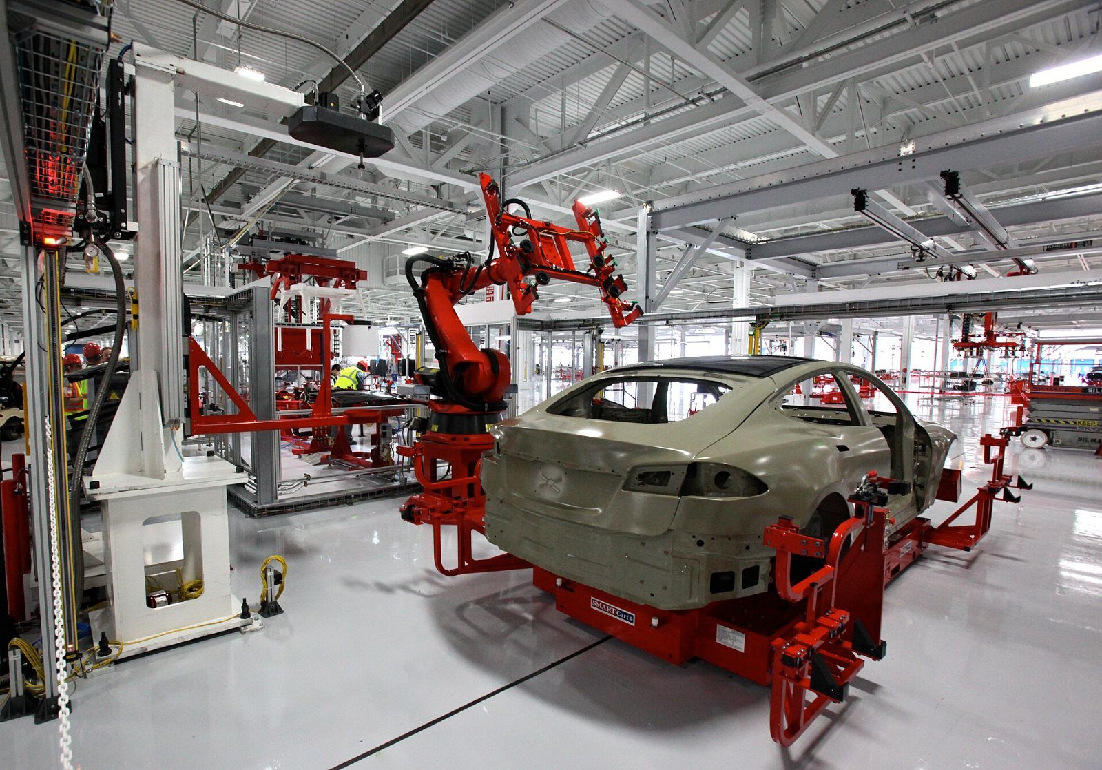 Red robot arms around a car body