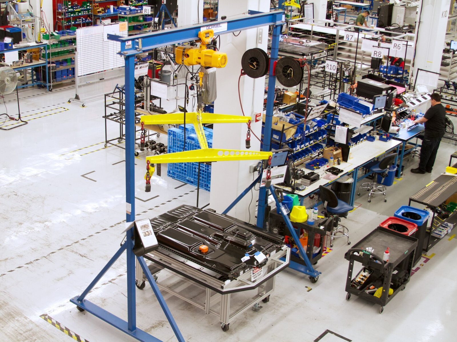 Tesla: Workbenches with tools and a hoist in a bright workshop