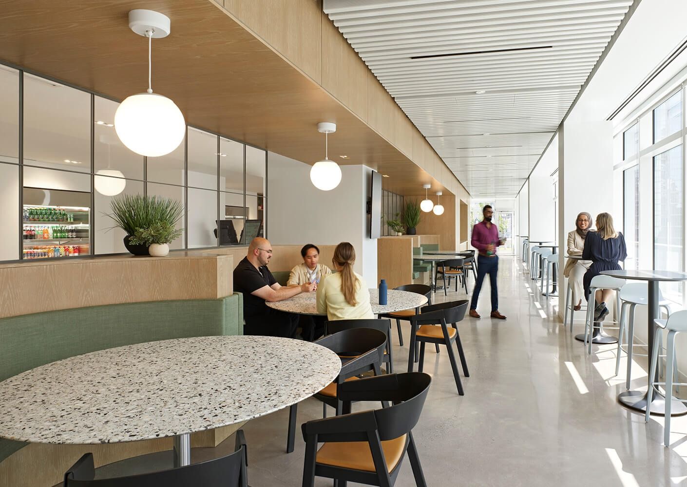 Thomson Reuters: A café with round terrazzo tables, booths and pendant lights