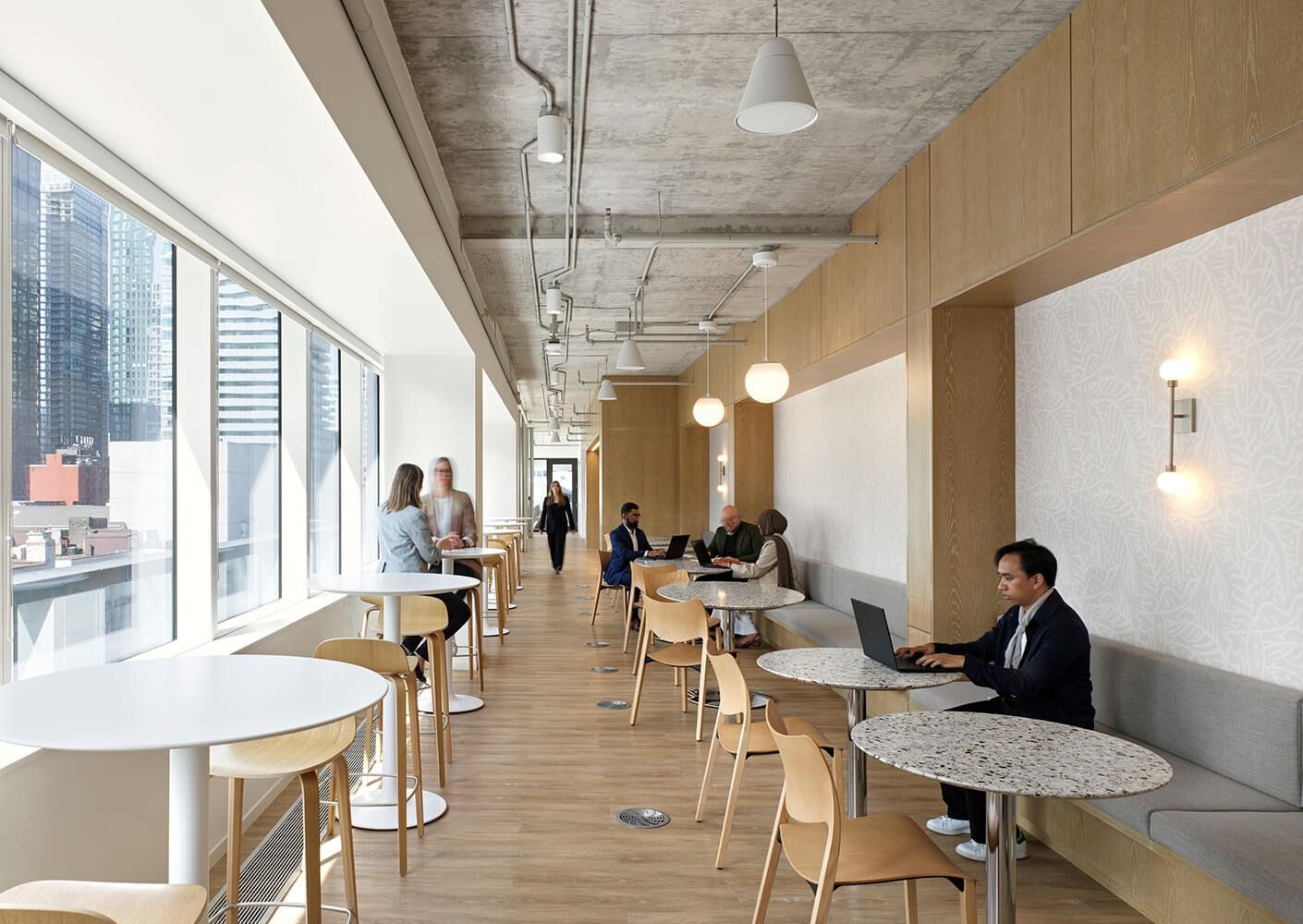 Thomson Reuters: A long window bar with stools and people working on laptops