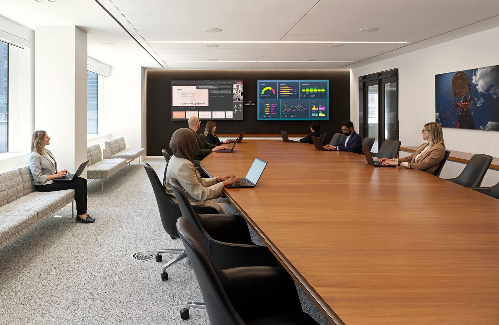 Thomson Reuters: A long wooden boardroom table with people on laptops and screens on the wall