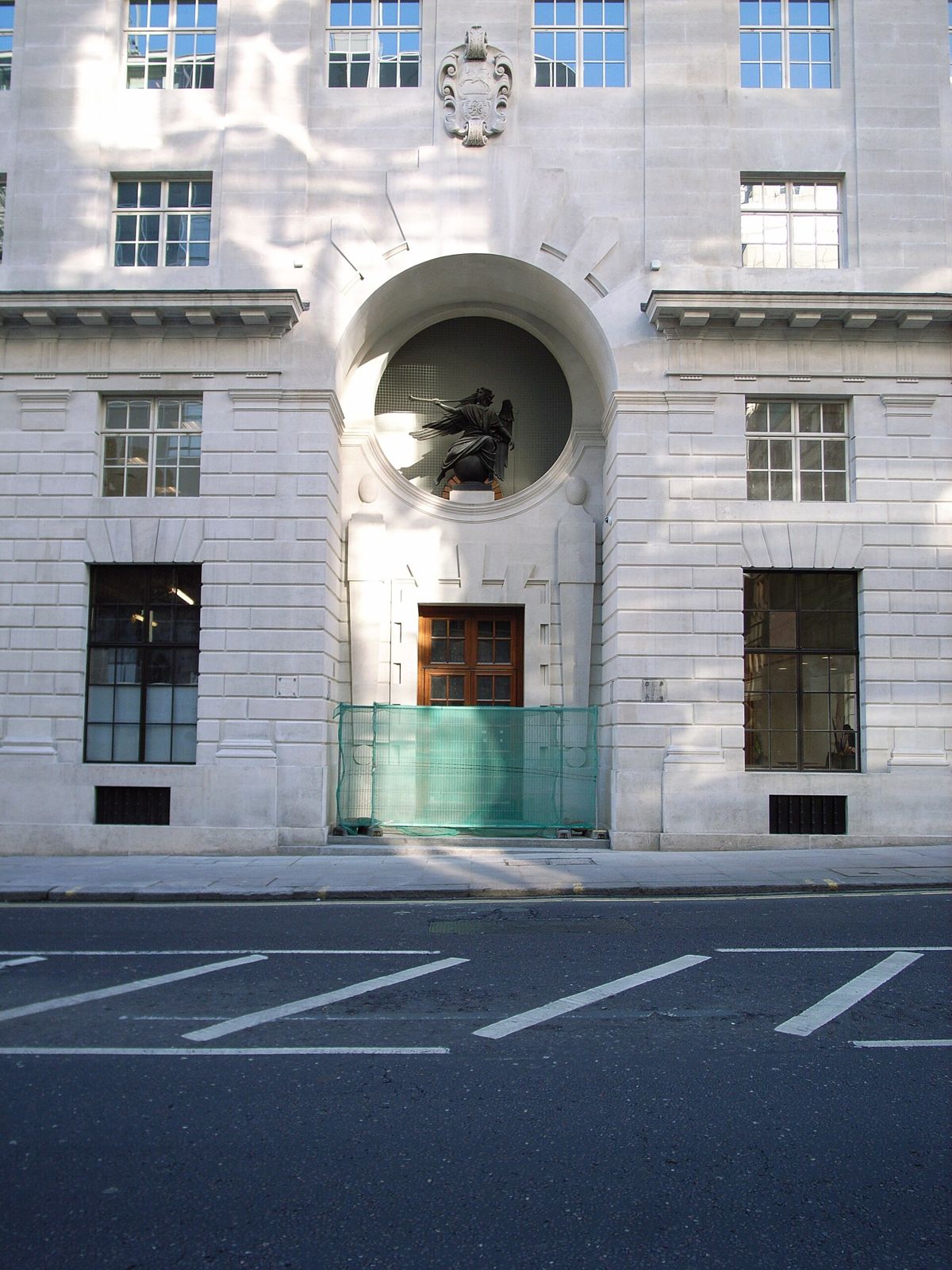 Thomson Reuters: A pale stone office facade with a large arched niche holding a sculpture
