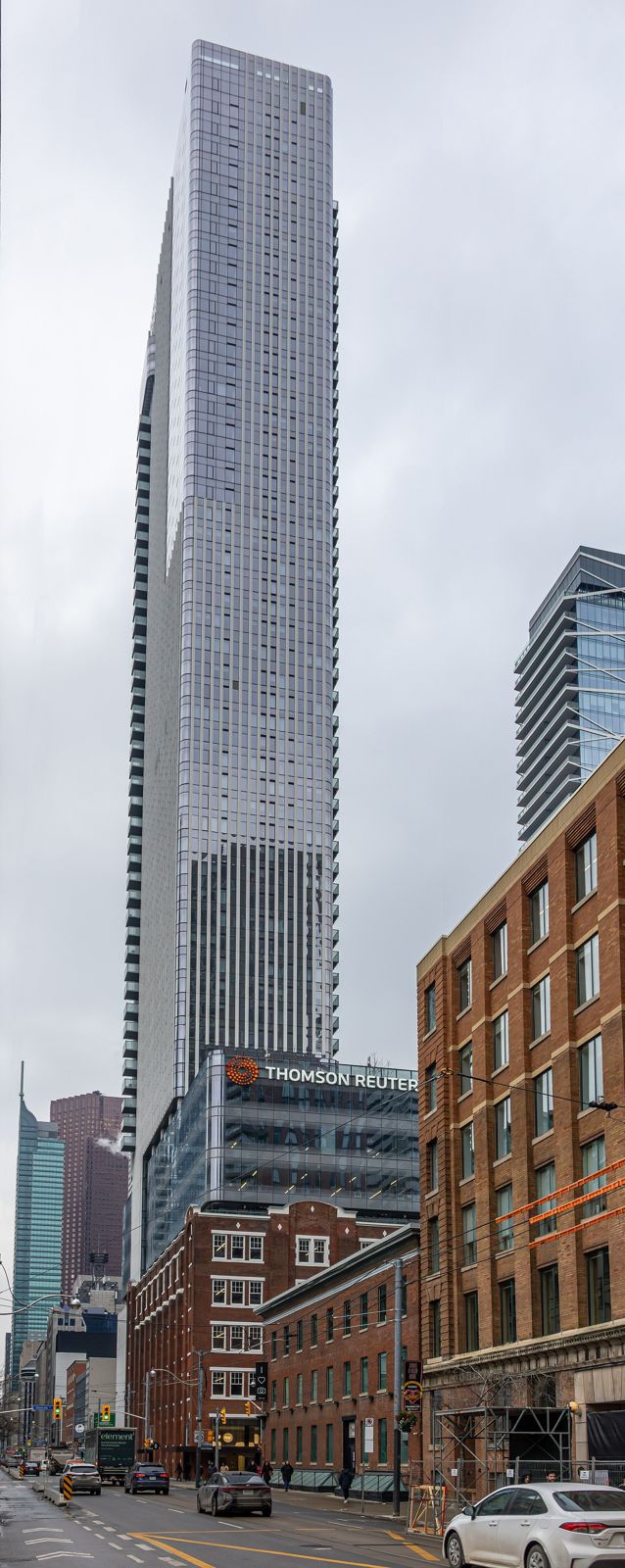 Thomson Reuters: A slim glass skyscraper rising above older brick buildings on a grey day