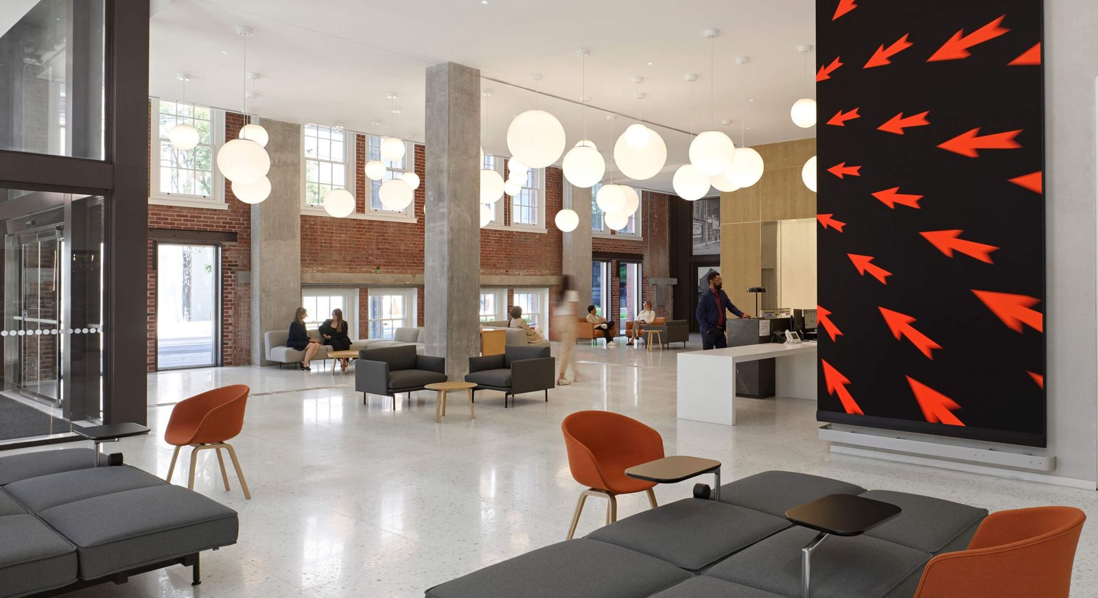 Thomson Reuters: An open lounge with grey sofas, orange chairs and a large red-and-black artwork