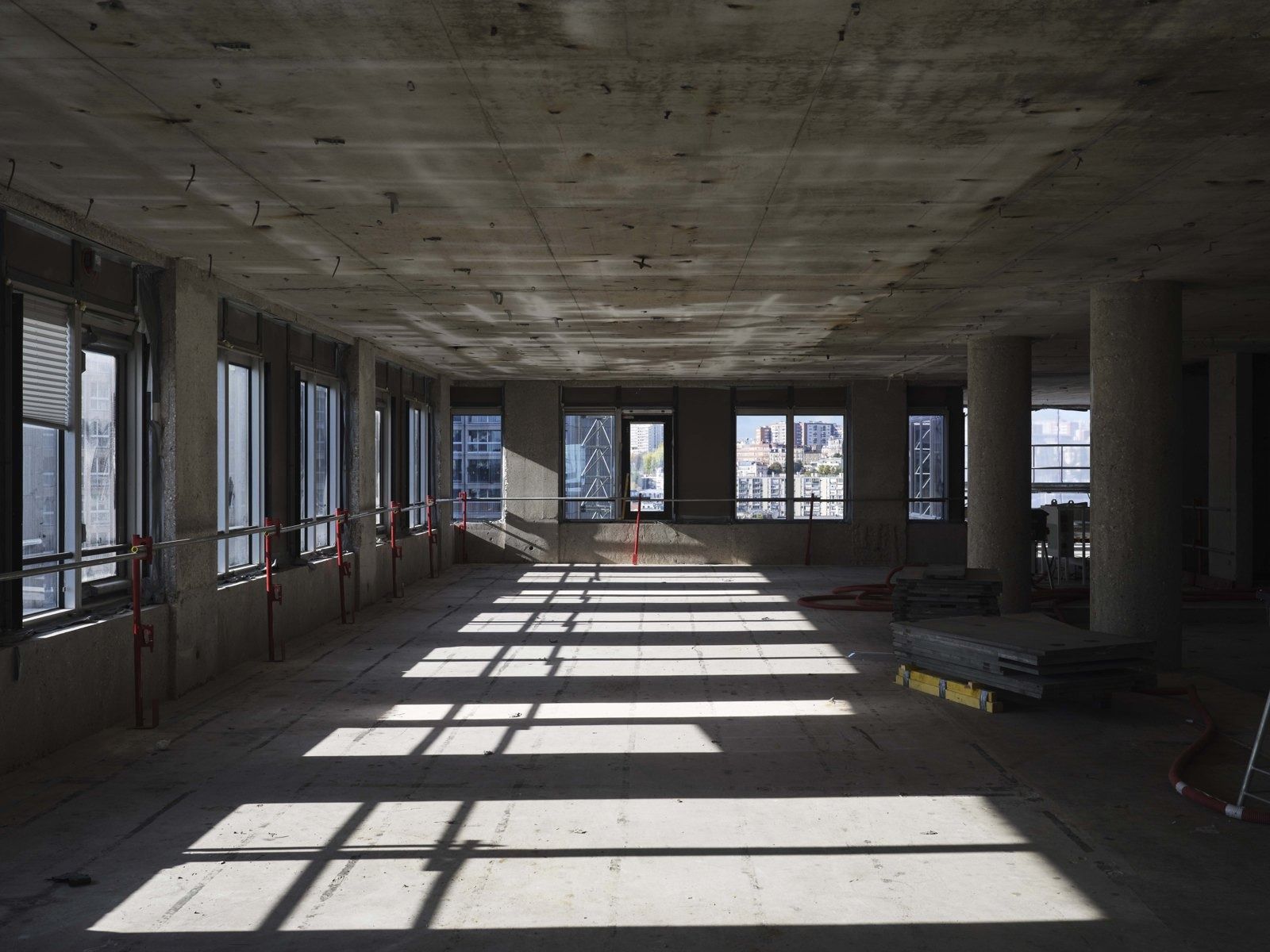 TotalEnergies: Empty office floor with long window bands and raw concrete